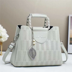 Detail of grey-green bucket bag featuring woven texture and decorative leaf pearl pendant