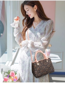 Asian model wearing a large capacity floral print handbag with pink straps and gold hardware