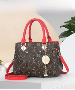Detail of a brown monogram tote bag with vibrant red handles and a gold star pendant