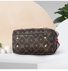 Detailed bottom view of brown leather handbag featuring golden metal feet and logo pattern