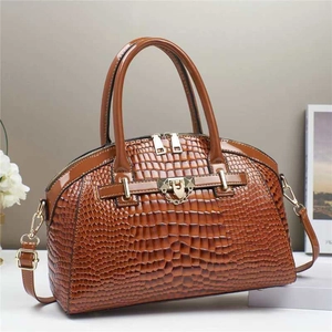 Détail d'un sac à main marron motif crocodile avec fermoir doré et chaîne décorative