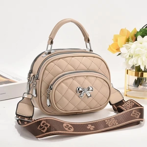 Détail du sac à main matelassé beige avec pendentif nœud argenté et bandoulière