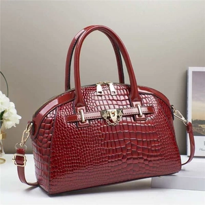 Détail du sac à main en cuir verni bordeaux à motif crocodile et finitions dorées