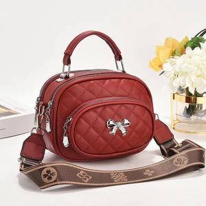 Détail du sac bandoulière matelassé rouge avec nœud argenté et large bandoulière fleurie