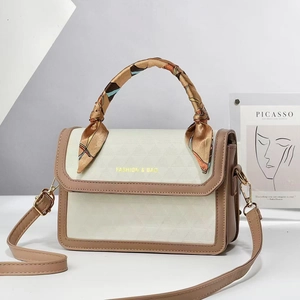 Detail of triangular embossed crossbody bag with scarf-wrapped handle and gold buckles