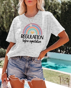 Detail of white cotton T-shirt featuring rainbow print and REGULATION text with denim shorts