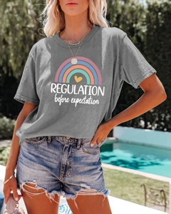 Detailed view of women's grey t-shirt with rainbow print and slogan in a summer setting