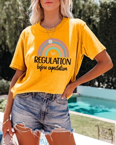 Macro shot of yellow cotton T-shirt featuring rainbow print and slogan text