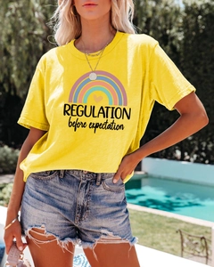 Close-up of yellow cotton t-shirt with rainbow print and slogan near an outdoor pool
