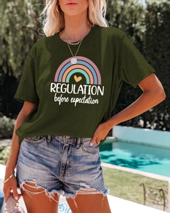 Detail of dark green T-shirt with rainbow print and slogan near a sunny pool