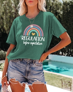 Close-up of rainbow graphic and text on a green cotton T-shirt worn by a model