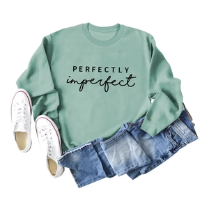 Mise à plat du sweat vert sauge avec imprimé PERFECTLY imperfect et un jean en denim