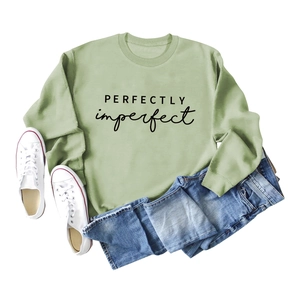 Détail du sweat vert sauge avec texte Perfectly Imperfect noir et tissu en coton doux