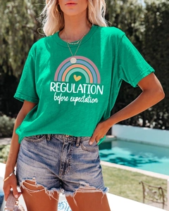 Detail of green T-shirt with rainbow print and Regulation before expectation text
