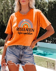 Detail of orange graphic T-shirt and distressed denim shorts in a poolside setting