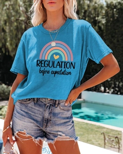Close-up of blue cotton T-shirt with rainbow print and text on model in outdoor setting