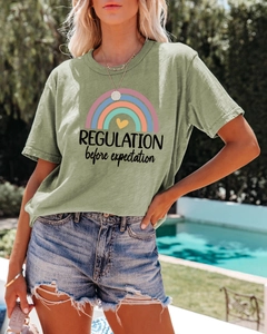 Close-up of green cotton T-shirt with rainbow print and 'REGULATION' graphic lettering