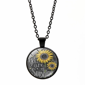 Détail du collier tournesol avec citation You Are My Sunshine sous un dôme de verre bombé