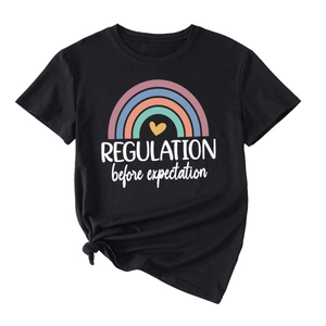Close-up of rainbow heart graphic and REGULATION typography on black cotton t-shirt