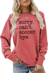 Detail of coral red soccer sweatshirt showing 'Sorry Can't Soccer Bye' print on fabric