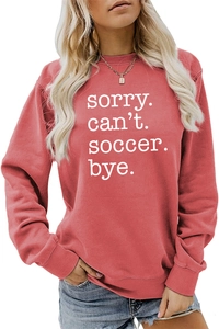 Detail of the white sorry can't soccer bye text print on a coral red sweatshirt
