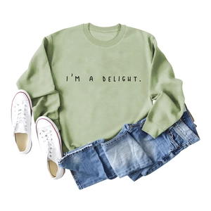 Flat lay of light green crewneck sweatshirt with I'M A DELIGHT text and denim shorts