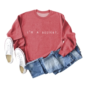 Flat lay of red crewneck sweatshirt with I'M A DELIGHT print and casual accessories