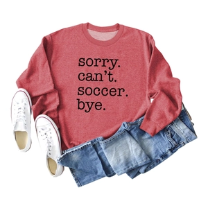Detailed flat lay of red crewneck sweatshirt with Sorry Can't Soccer Bye letter print