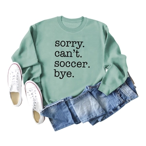 Flat lay of light green soccer slogan sweatshirt with denim jeans and white sneakers