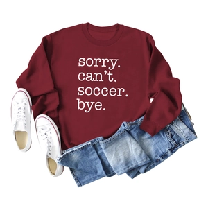 Flat lay of burgundy soccer slogan sweatshirt with denim jeans and canvas sneakers