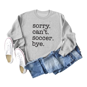 Flat lay of gray soccer slogan sweatshirt with denim jeans and white sneakers