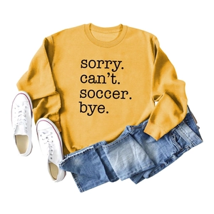 Detail of yellow sweatshirt with Sorry Can't Soccer Bye text and denim styling