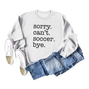 Flat lay of white sweatshirt featuring bold 'SORRY. can't. soccer. bye.' text print