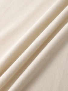 Close-up of soft beige knitted cotton fabric texture showing detailed weave and drape