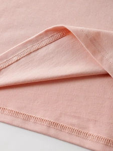 Detailed macro view showing the double-needle stitching and pink knit fabric of the T-shirt