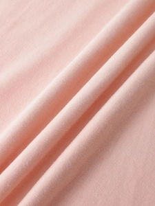 Macro detail of soft pink knit cotton fabric texture showing fine weave and soft drape