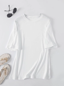 Flat lay of a white oversized crewneck T-shirt with summer sandals and sunglasses