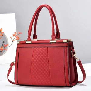 Detail of red quilted leather handbag with lychee texture and gold-tone hardware