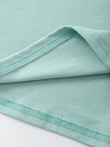 Close-up of double-needle hem stitching and knit texture on mint green cotton t-shirt