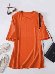 Flat lay of an oversized orange cotton t-shirt styled with sunglasses and sandals