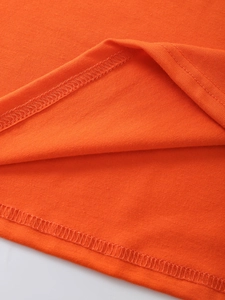 Close-up of double-stitched hem on orange cotton knit shirt showing detailed sewing quality