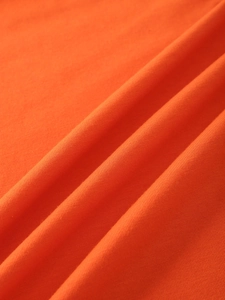 Close-up of orange knitted T-shirt fabric showing soft texture and fine ribbed details