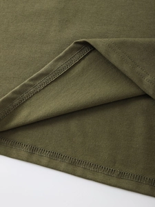 Detailed macro view of olive green T-shirt hem featuring professional double-needle stitching