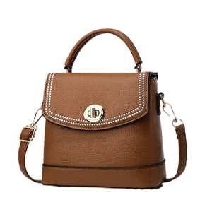 Brown faux leather crossbody bag with top handle and golden rivets on front flap