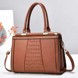 Detailed view of brown tote bag with crocodile texture panels and gold metal hardware