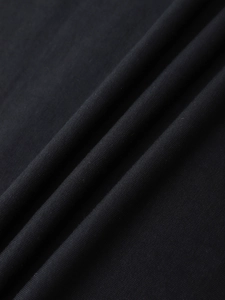 Detailed macro view of black knitted fabric texture with fine ribbing on a loose fit t-shirt