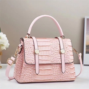 Detail of pink faux crocodile leather handbag with golden hardware and top handle