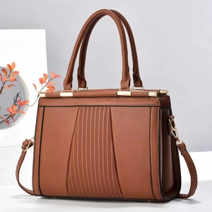 Brown leather tote bag with pleated texture and golden hardware on a minimal display