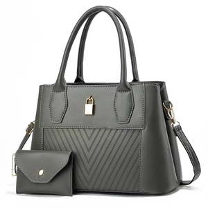 Detail of grey quilted tote bag set with golden padlock and detachable shoulder strap