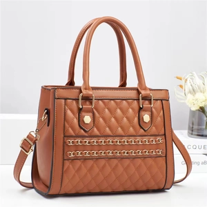 Detailed shot of brown quilted crossbody bag with gold chain and metal rivet accents
